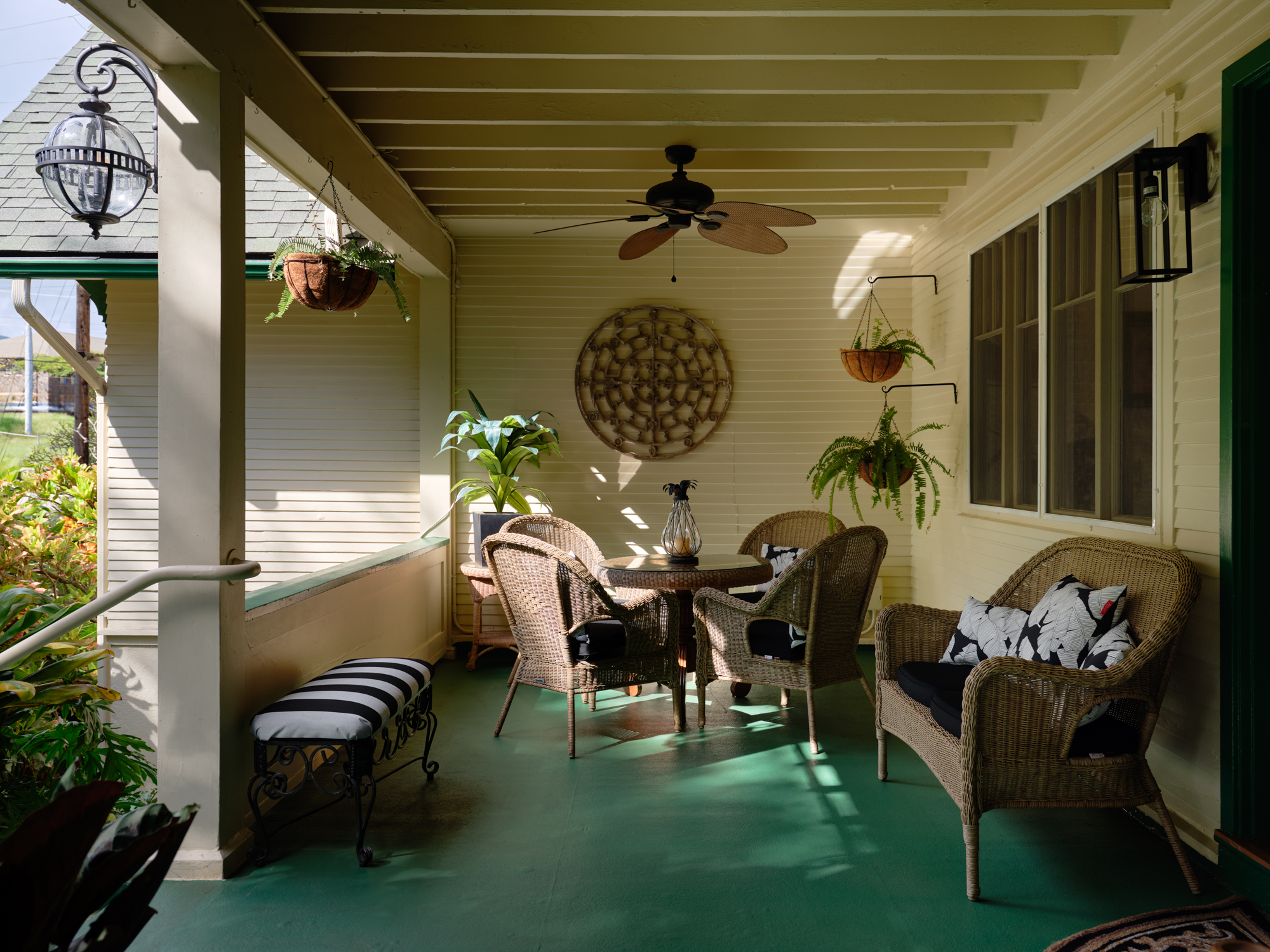 The covered lanai — wicker seating, ferns, open to the garden